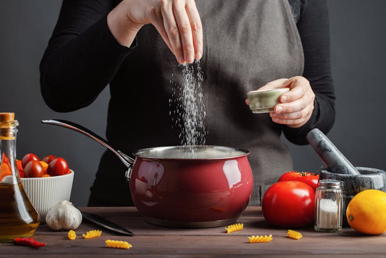 Chef sprinkling salt into a pot