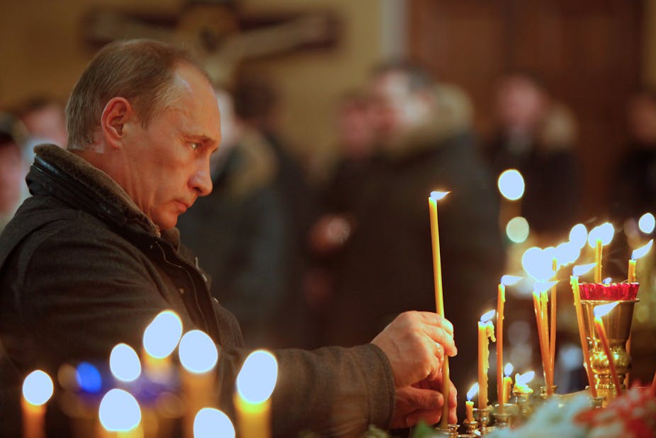 Russia's President Vladimir Putin lighting a candle in an Orthodox Church.