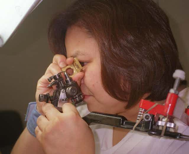 A woman looks through a contraption at a diamond