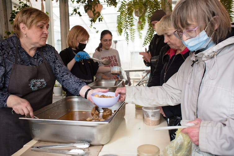 Ukrainian volunteers serve free meals to elderly people.