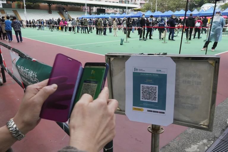 a pair of hands point a smart phone at a sign containing a black and white pattern