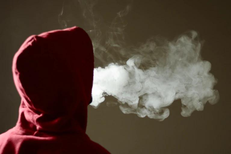 Person wearing hooded top exhaling smoke