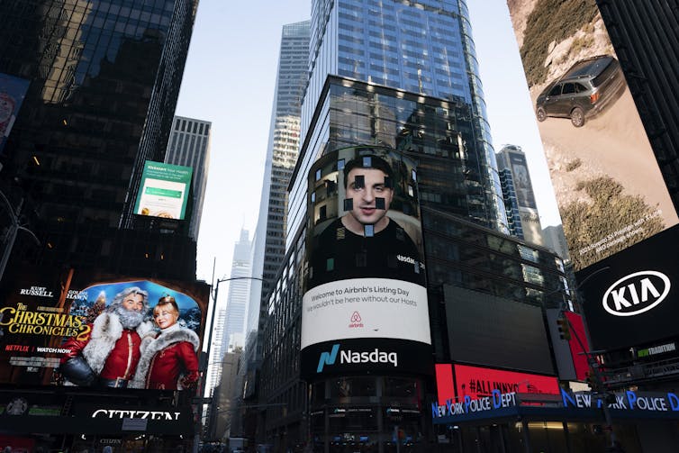 Brian Chesky's image on an electronic screen outside the Nasdaq stock market in New York's Time Square to mark Airbnb's initial public offering on December 10 2020.