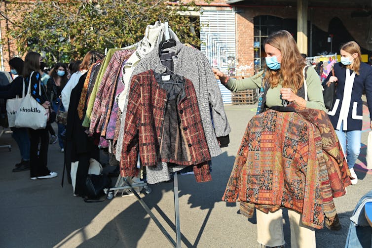 Person browses second hand clothes at market