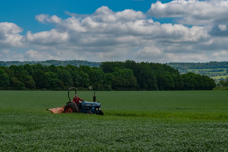 A person drives a tractor across a green field