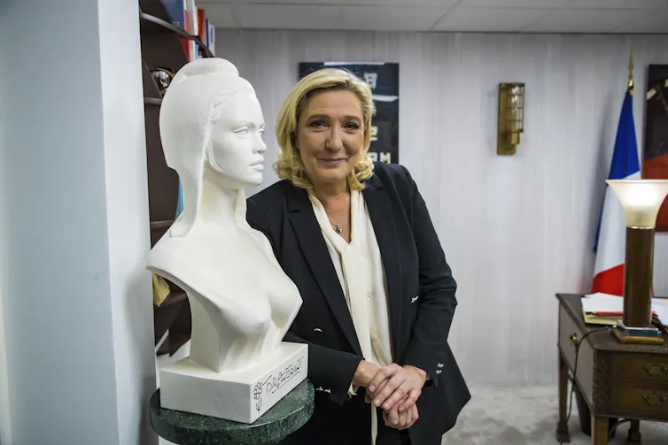 Marine Le Pen posing next to a bust of Marianne – symbolic figure of the French republic.