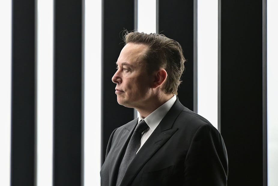 Side shot of Elon Musk against black and white vertical stripes