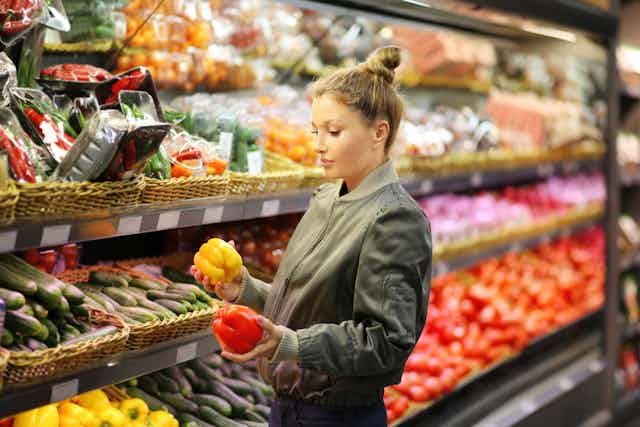 Young female by fruit and vegetables in a grocery store