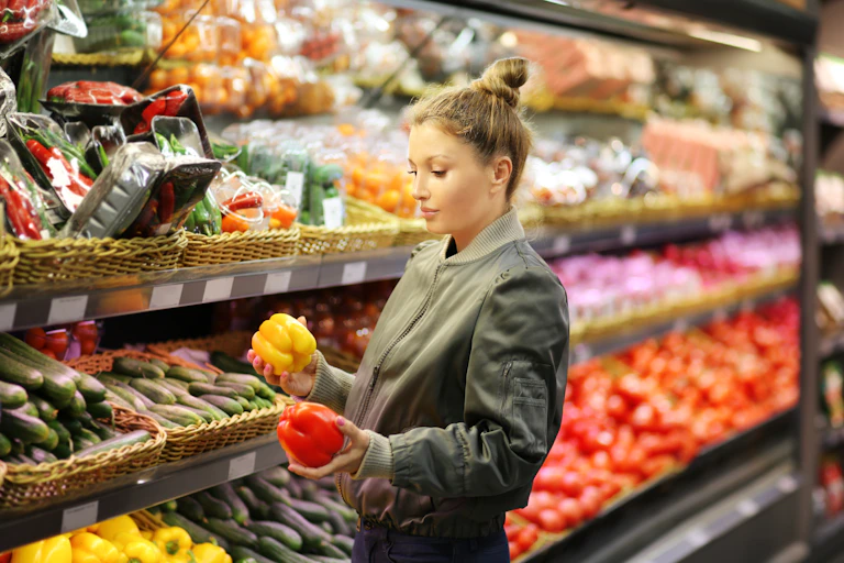 Young female by fruit and vegetables in a grocery store