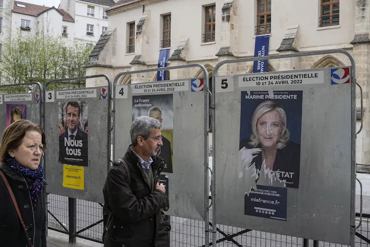 Des gens passent devant des affiches électorales