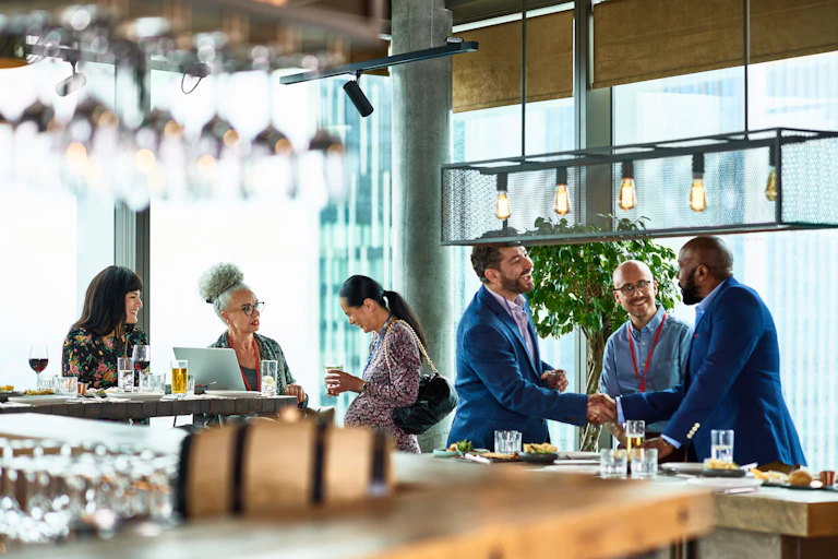 A group of men and a group of women in business attire at a bar.