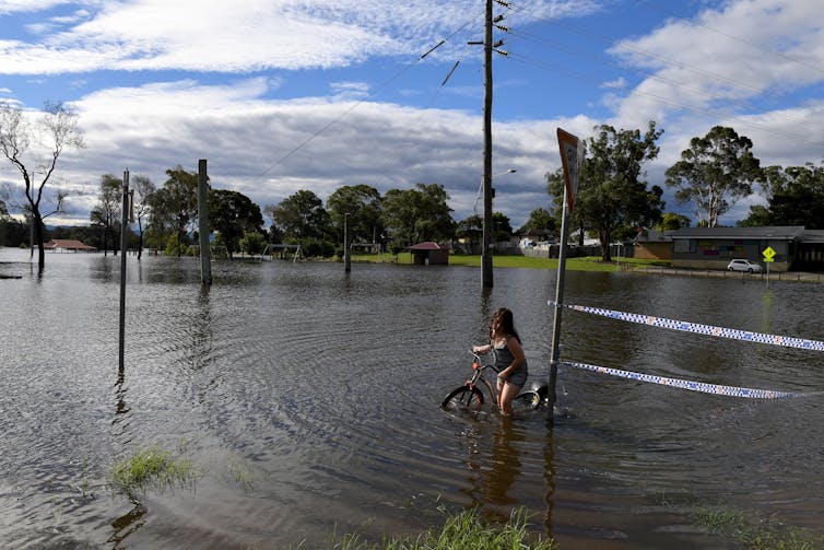 Child rides bike through floodwater