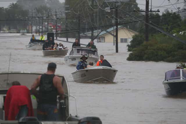 Residents drive boats through floodwater