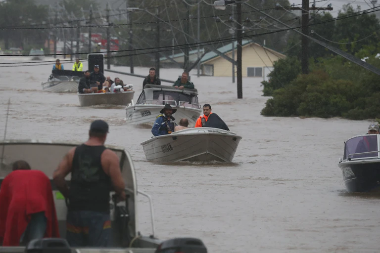 Residents drive boats through floodwater
