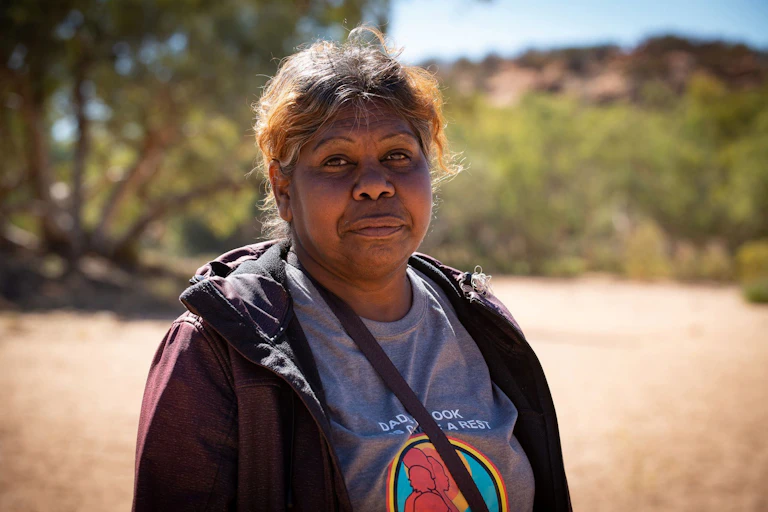A First Nations person, R Rubuntja stands in the sunlight.