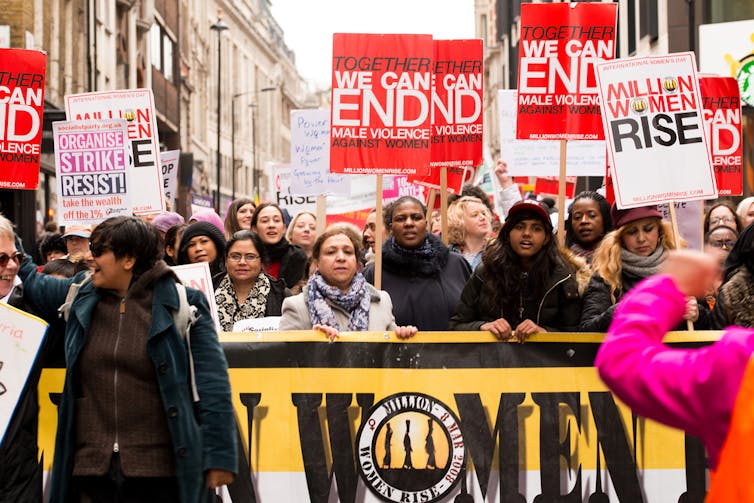 Group of women holding signs and protesting at a domestic violence awareness march.