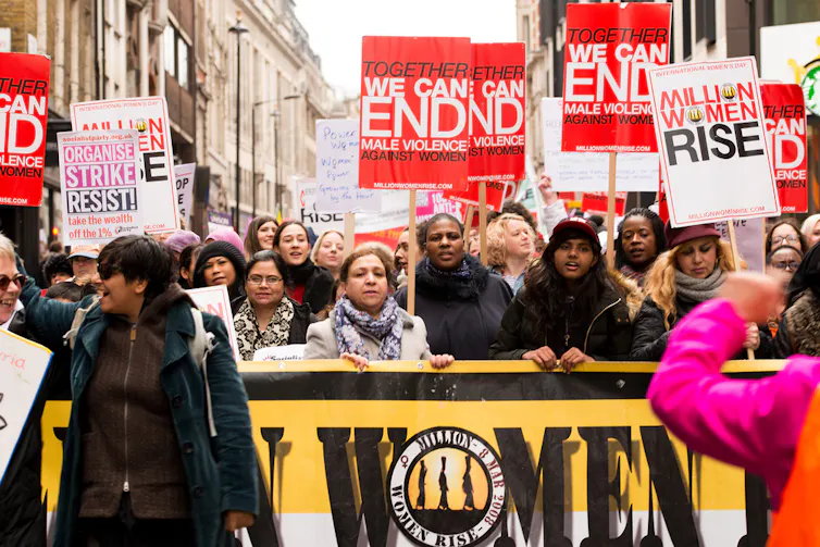 Group of women holding signs and protesting at a domestic violence awareness march.