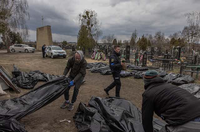Forensic investigators assemble bodies in body bags for examination in Bucha, Ukraine, April 2022.