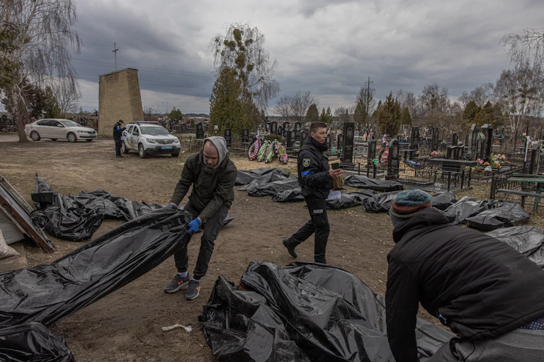 Forensic investigators assemble bodies in body bags for examination in Bucha, Ukraine, April 2022.