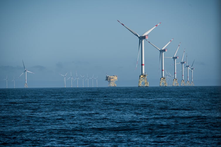Wind turbines arranged in a row far out at sea.