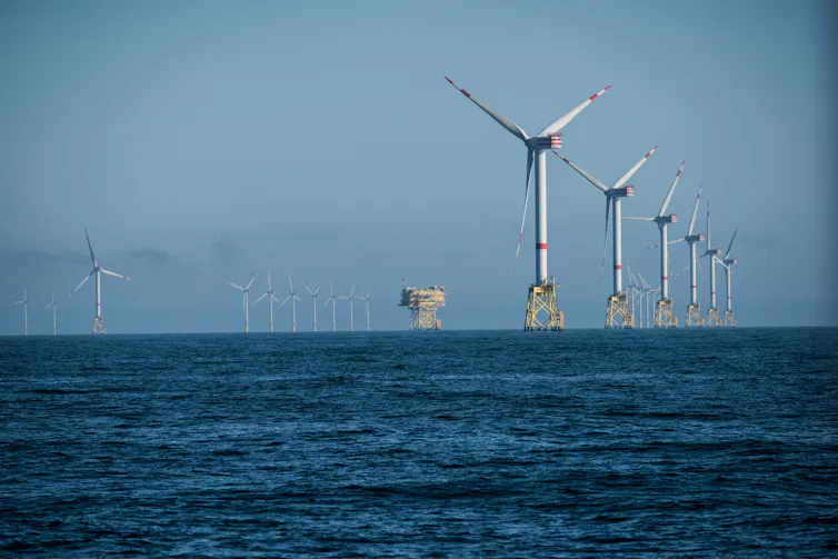 Wind turbines arranged in a row far out at sea.