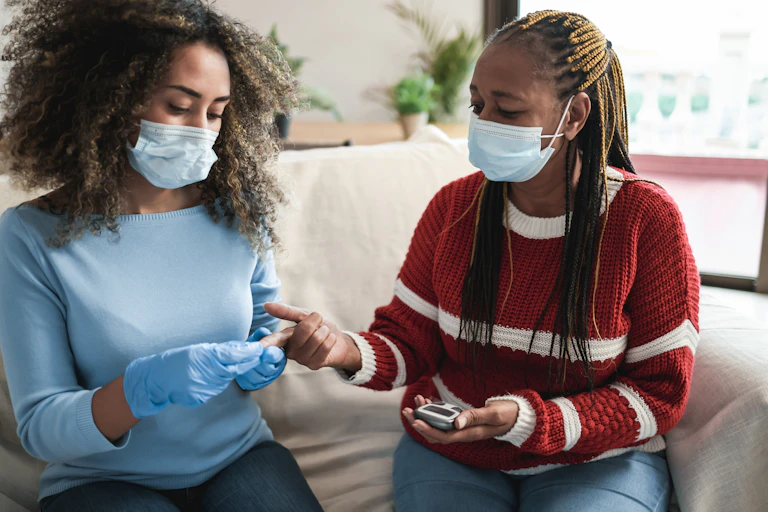 A woman has her blood sugar measured with a finger prick by a nurse.