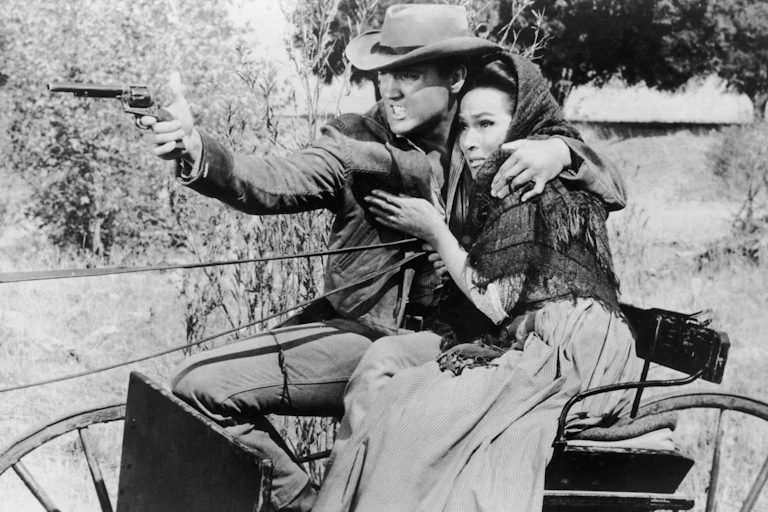 Man draws woman closer to him to protect her as he fires a gun.