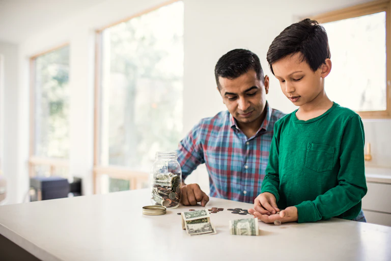 A father and son count coins and dollar bills together.