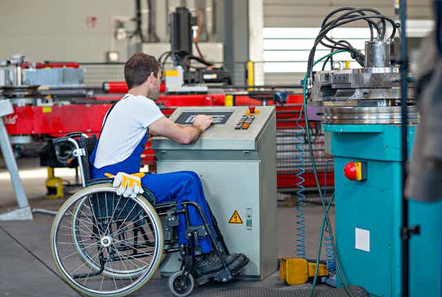 Un homme en fauteuil roulant travaille dans une usine.