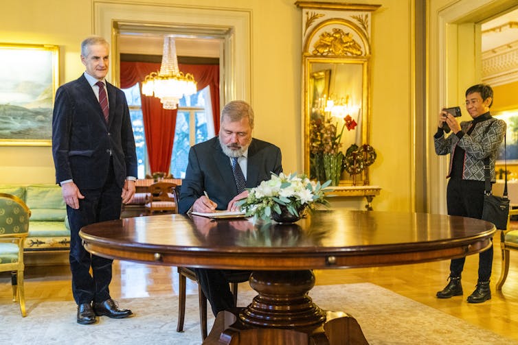 Nobel laureate, Dmitry Muratov, the owner of Russian independent newspaper Novaya Gazeta, signing a guest book at a table in the house of Norwegian prime minister Jonas Gahr Store.