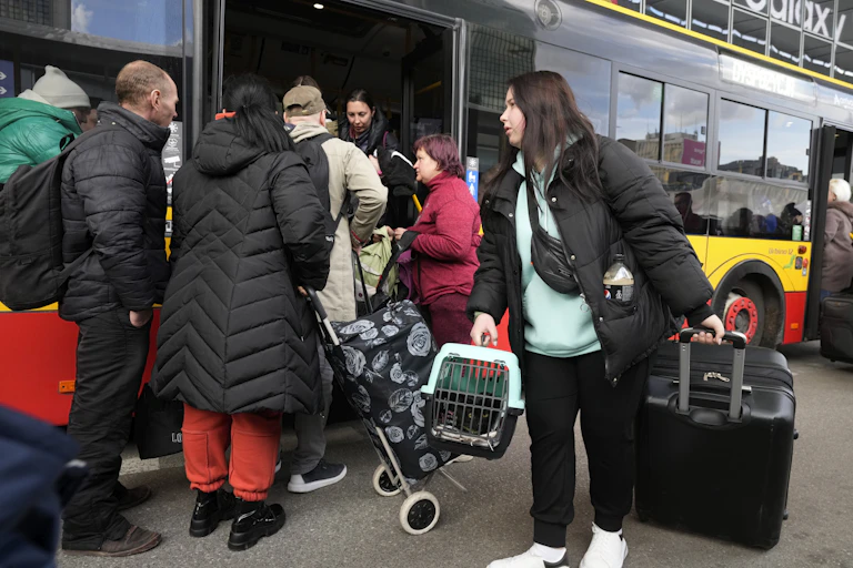 People carrying luggage, animals board a bus.