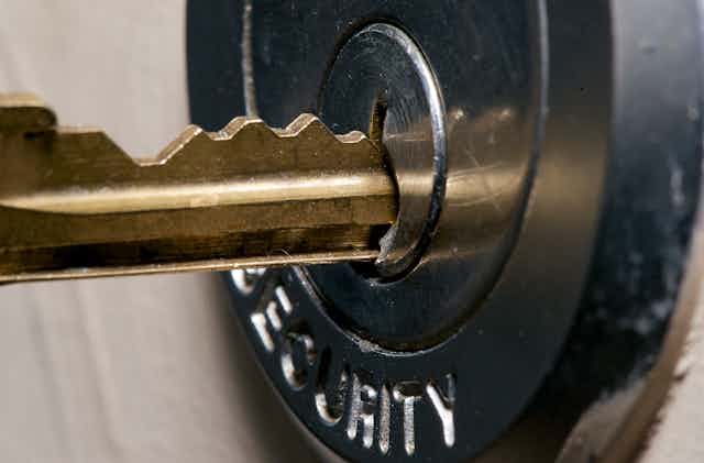Close up shot of a metal key being inserted into a lock.