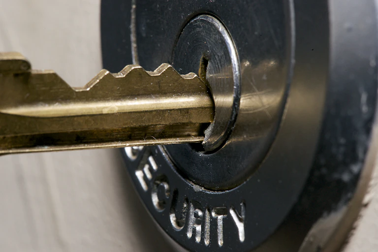 Close up shot of a metal key being inserted into a lock.