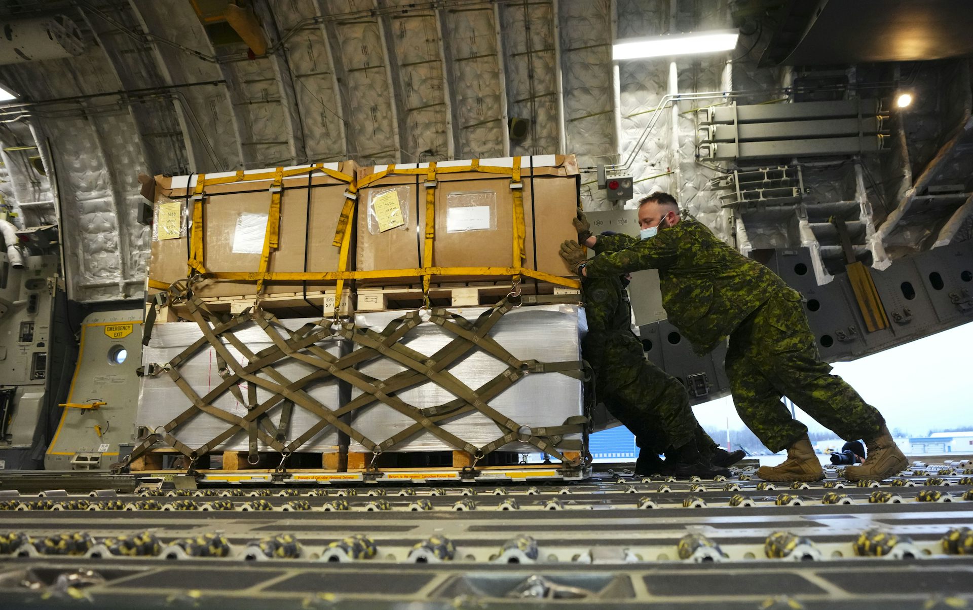 two uniformed men push a large crate