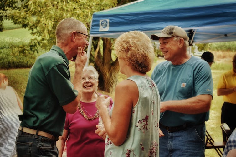 four adults chatting at an outdoor gathering