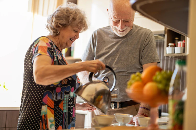 older couple make tea together in kitchen