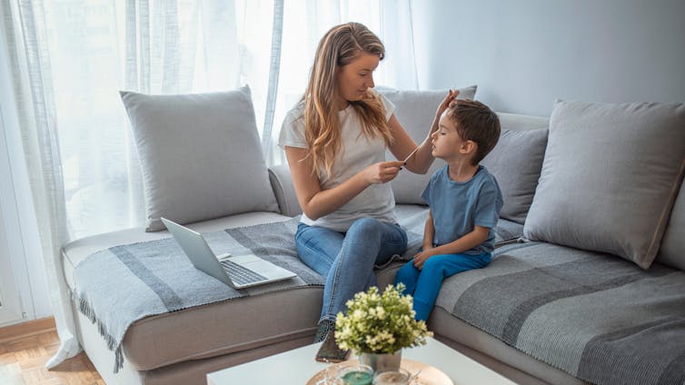 A woman administers a lateral flow test to her son at home.