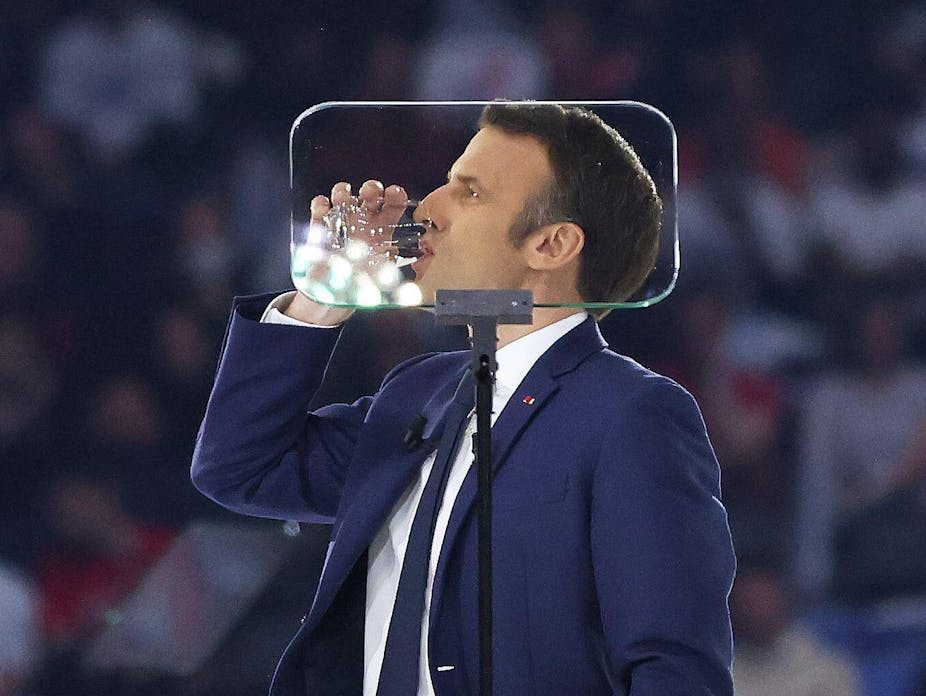 Macron drinking from a glass of water behind an autocue