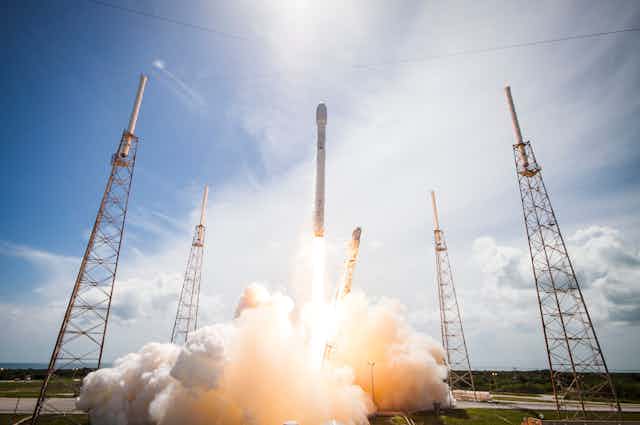 A SpaceX rocket launches against a blue sky