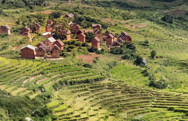 A stretch of land on a green mountainous terrain with a handful of wooden homes.
