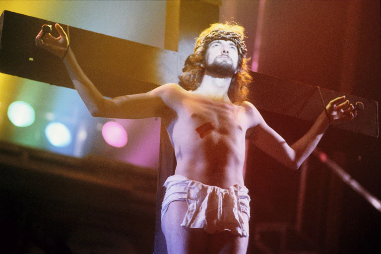 A man playing Jesus in a play in front of a cross.