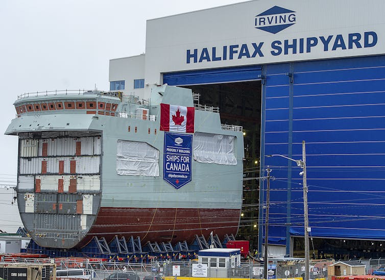 the centre block of a future patrol ship is seen outside a shipbuilding facility that says halifax shipyard