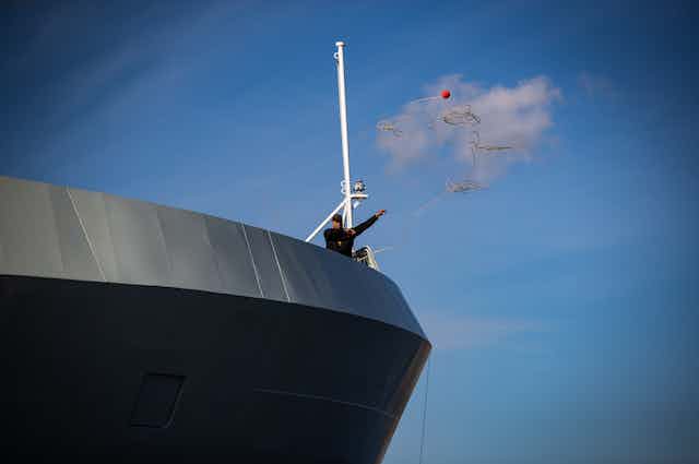 a crew member tosses a line from a patrol ship