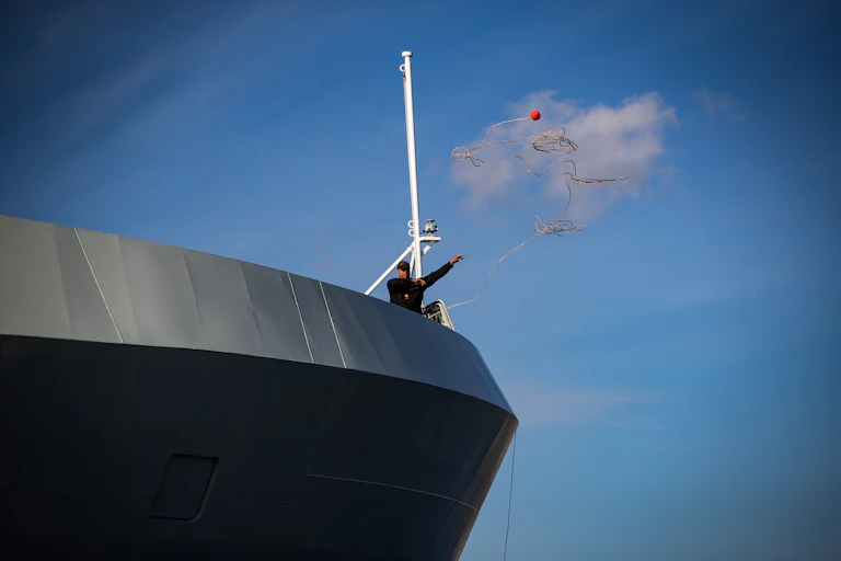a crew member tosses a line from a patrol ship