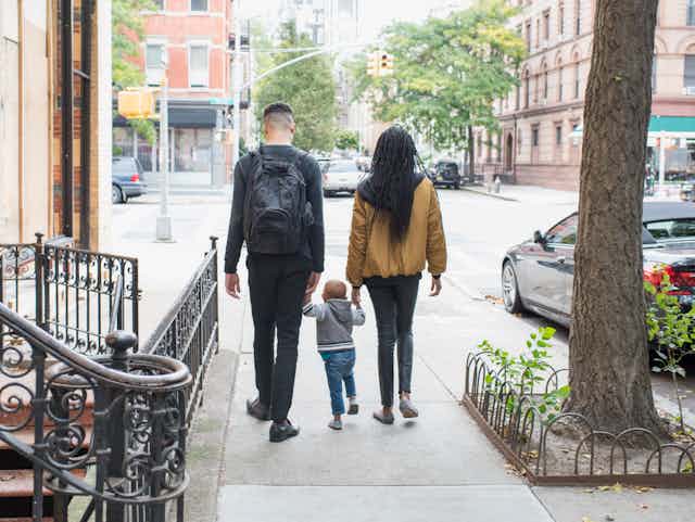 family walking away from camera on city sidewalk
