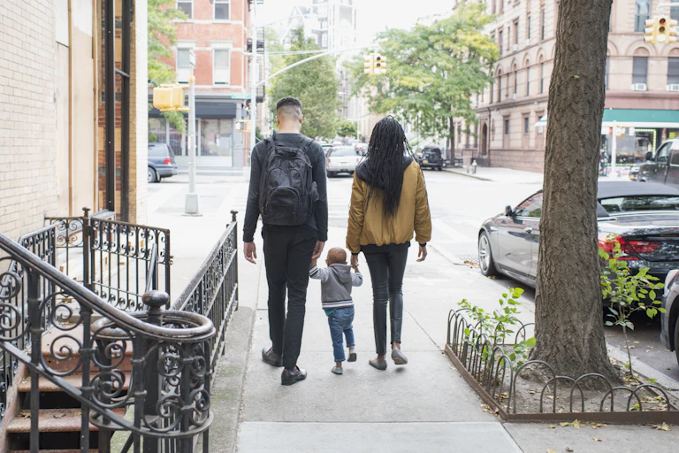 family walking away from camera on city sidewalk