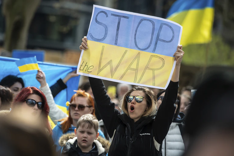 Person holding sign of Ukraine flag saying 'stop the war'
