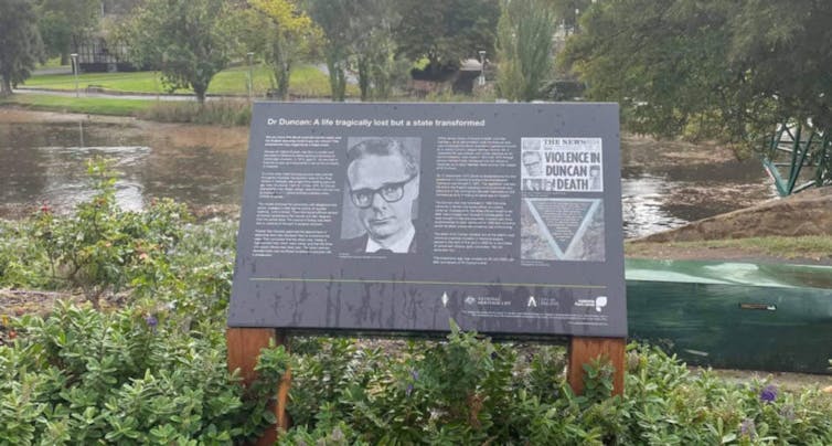 A memorial plaque by a river.