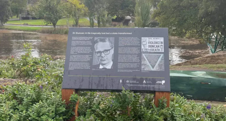 A memorial plaque by a river.
