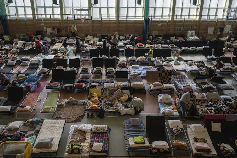 People who fled the war in Ukraine rest inside an indoor sports stadium being used as a refugee center